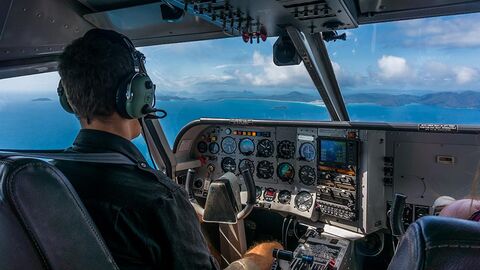Pilot sitzt im Cockpit eines Flugzeugs und schaut in die Wolken.