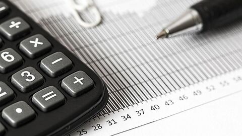 Taschenrechner und Tabellenblatt liegen auf einer ebenen Fläche.