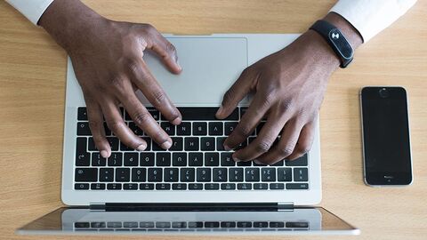 Hände tippen auf der Tastatur eines Notebooks.