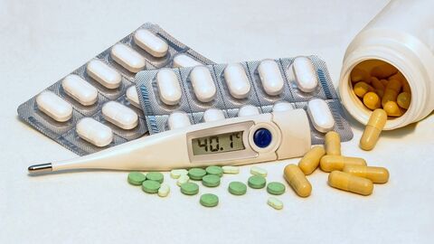 Zwei Schachteln mit Pillen gefüllt, eine Dose mit Pillen, offen, liegend, ein Fieberthermometer.