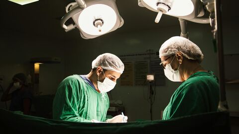 Zwei Ärzte stehen an einem beleuchteten Operationstisch.