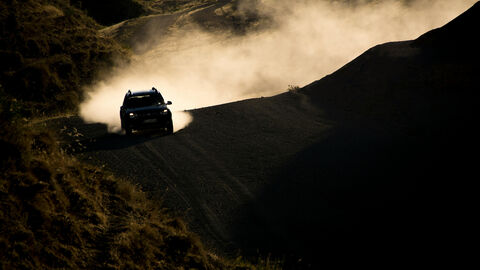 Rallye-Auto  fährt auf einem Weg in bergiger Landschaft.